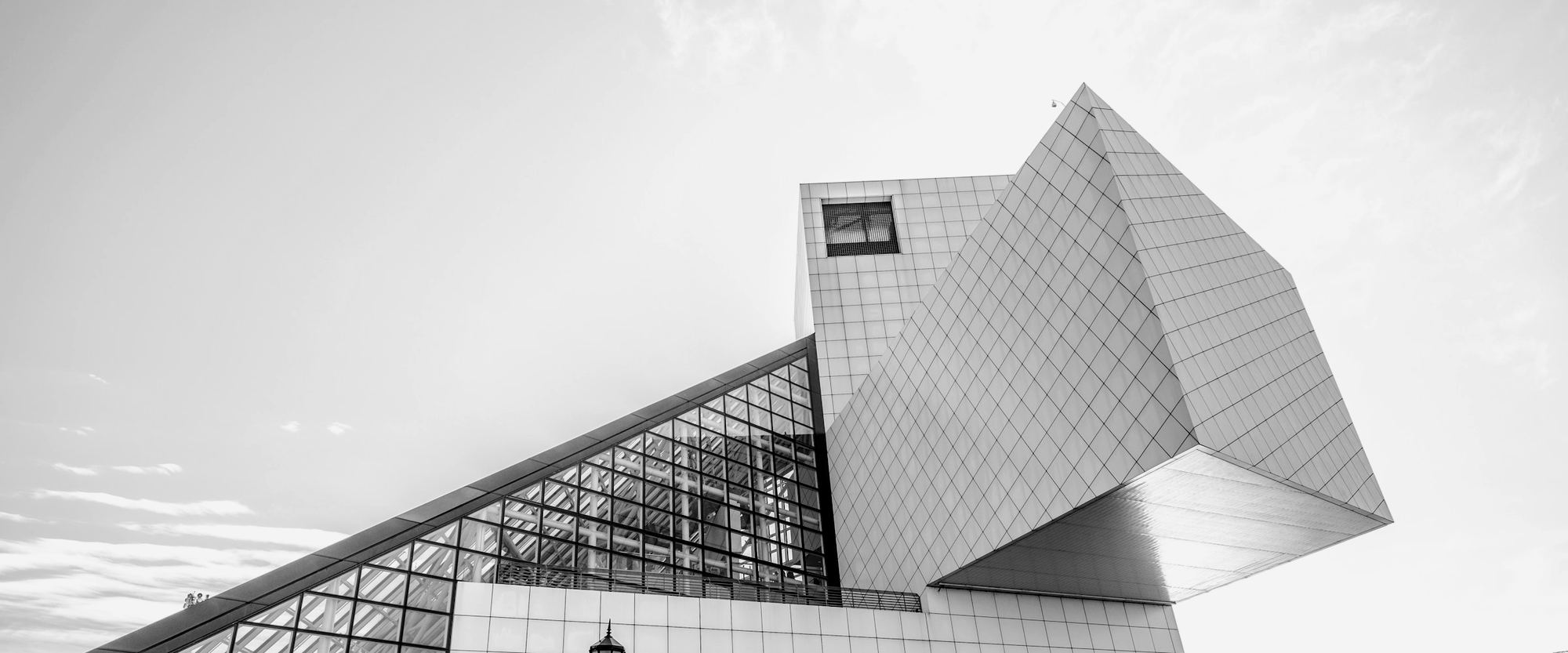 An angular modern building of faceted panels against a bright sky.